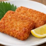 白い皿にがんすを2枚盛り、大葉とレモンを添えたシンプルな料理写真風